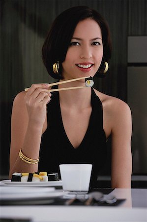 front of expensive house - A woman looks at the camera as she eats sushi Stock Photo - Premium Royalty-Free, Code: 656-01766569