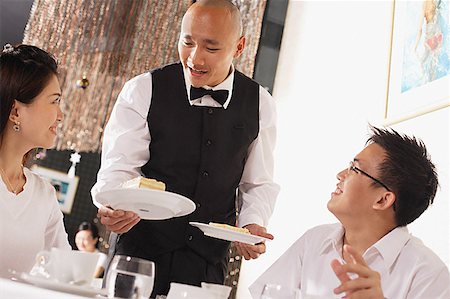 Waiter serving plates of dessert to customers in restaurant Stock Photo - Premium Royalty-Free, Code: 656-01767907