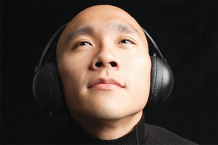 Man with shaved head, wearing headphones Stock Photo - Premium Royalty-Free, Code: 656-01768049