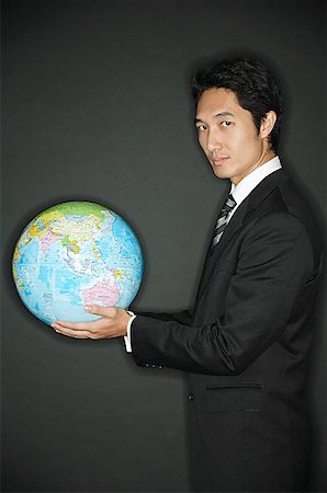 Businessman holding globe in hands, looking at camera Stock Photo - Premium Royalty-Free, Code: 656-01768974