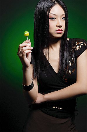 Young woman in black dress, holding green lollipop Stock Photo - Premium Royalty-Free, Code: 656-01770640