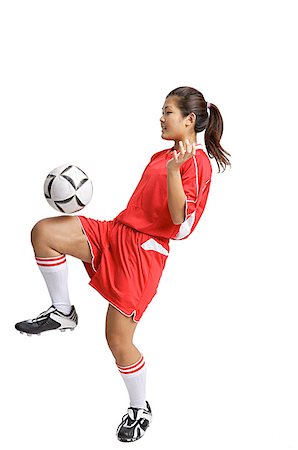 Young woman in soccer uniform, balancing ball on knee Stock Photo - Premium Royalty-Free, Code: 656-01771334