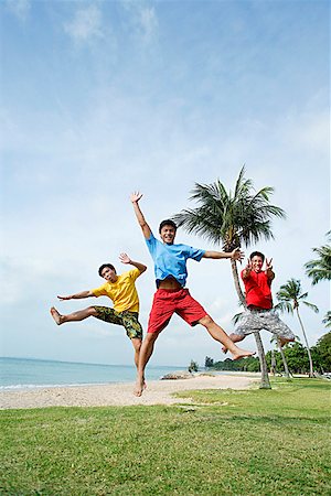 Three men  on beach, jumping in air, looking at camera Stock Photo - Premium Royalty-Free, Code: 656-01772837