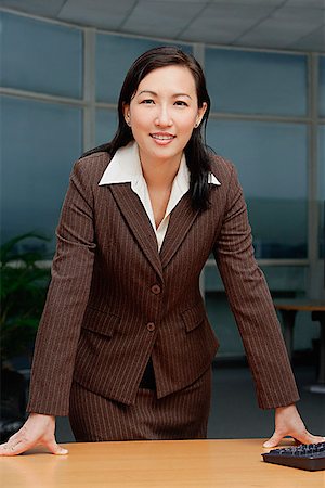 Businesswoman leaning on table, looking at camera Stock Photo - Premium Royalty-Free, Code: 656-01772935