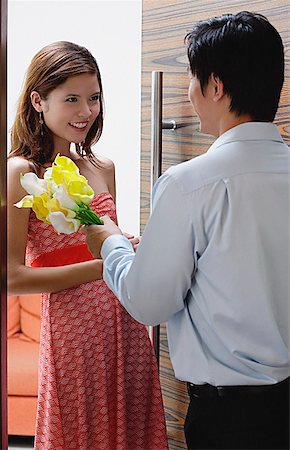 Couple standing at doorway, man giving woman flowers Stock Photo - Premium Royalty-Free, Code: 656-01773455