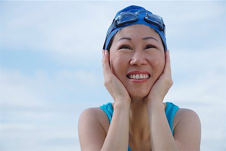 Mature woman wearing swim cap and goggles, hands on face, looking away Stock Photo - Premium Royalty-Free, Code: 656-01773598