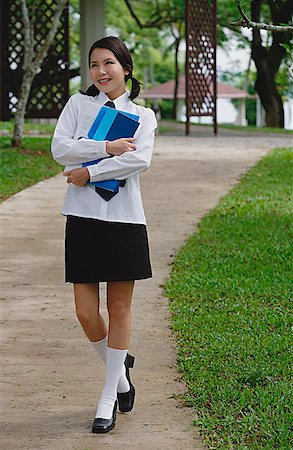 Young woman in school uniform, walking on path Stock Photo - Premium Royalty-Free, Code: 656-01773945