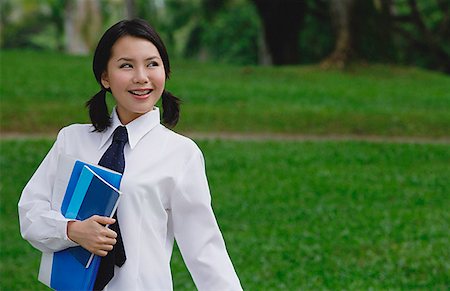 Young woman in school uniform, standing in park, looking away Stock Photo - Premium Royalty-Free, Code: 656-01773947