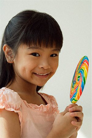 Girl with big lollipop smiling at camera Stock Photo - Premium Royalty-Free, Code: 656-01828910