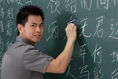 man writing Chinese characters on chalk board Stock Photo - Premium Royalty-Free, Code: 656-02879643