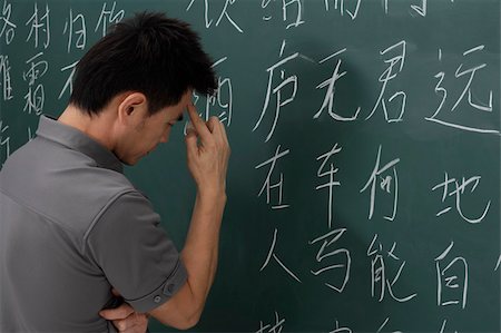man thinking in front of Chinese characters on chalk board Stock Photo - Premium Royalty-Free, Code: 656-02879681