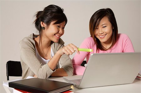Two women sitting at desk and using a laptop. Stock Photo - Premium Royalty-Free, Code: 656-03076294