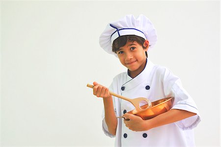 A boy dressed as a chef holding a mixing bowl and a wooden spoon Stock Photo - Premium Royalty-Free, Code: 659-06151808