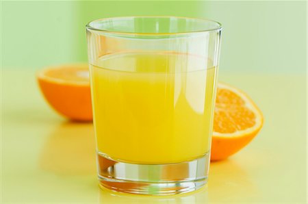 simsearch:659-06495307,k - A glass of orange juice with orange halves behind it Stock Photo - Premium Royalty-Free, Code: 659-06152914