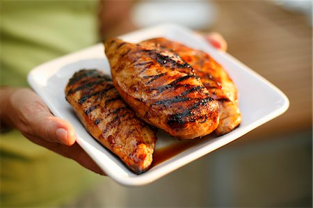 Woman Holding a Platter with Three Grilled Chicken Breasts Stock Photo - Premium Royalty-Free, Code: 659-06152950