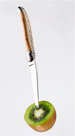 Knife sticking into half of a kiwi fruit Stock Photo - Premium Royalty-Free, Code: 659-06185018