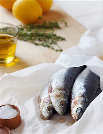 saltwater fish - Fresh Sardines on Parchment Paper with Salt, Lemon and Herbs Stock Photo - Premium Royalty-Free, Code: 659-06186542