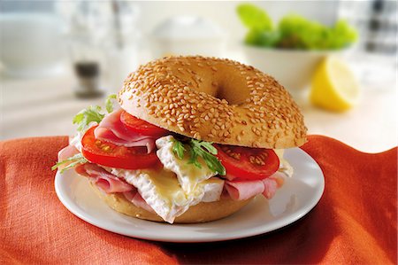 A sesame seed bagel with brie, ham and tomatoes Stock Photo - Premium Royalty-Free, Code: 659-06187932