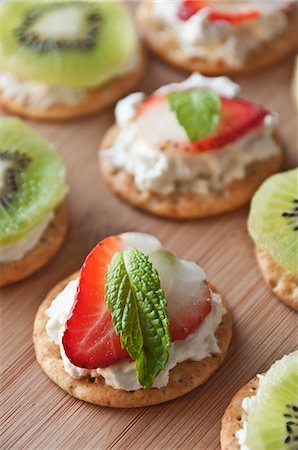Crackers Topped with Cream Cheese, a Strawberry Slice and a Mint Leaf; Some Topped with Cream Cheese and Kiwi Stock Photo - Premium Royalty-Free, Code: 659-06188426