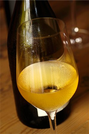 simsearch:659-06186663,k - A glass of white wine in front of a bottle Stock Photo - Premium Royalty-Free, Code: 659-06188465