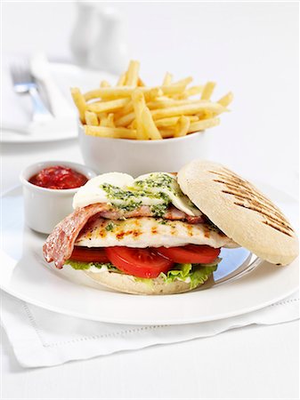 Chicken burger with bacon, mozzarella and pesto and a side of chips Stock Photo - Premium Royalty-Free, Code: 659-06183947