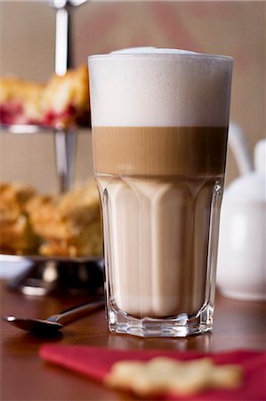 A latte macchiato in front of a cake stand Stock Photo - Premium Royalty-Free, Code: 659-06306415