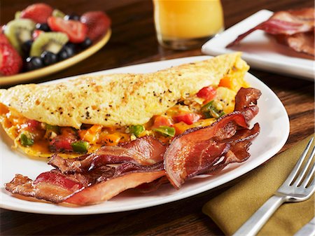 egg dish - Strips of Smoked Bacon with a Veggie Omelet on a White Dish' Fruit Salad and Orange Juice Stock Photo - Premium Royalty-Free, Code: 659-06307429