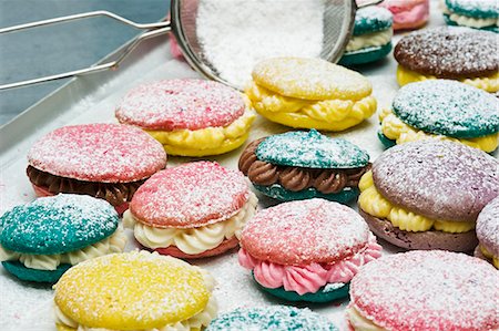 Various macaroons dusted with icing sugar on a baking tray Stock Photo - Premium Royalty-Free, Code: 659-06372473