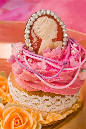 rococo - A cupcake decorated with buttercream and a Marie Antoinette pendant Stock Photo - Premium Royalty-Free, Code: 659-06372490