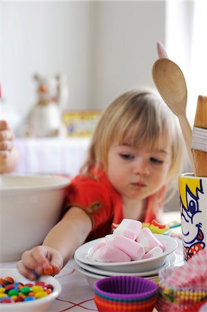 Young girl reaching for sweets from the bowl while baking Stock Photo - Premium Royalty-Free, Code: 659-06372518