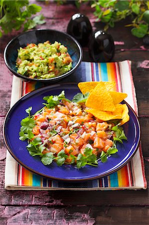 simsearch:659-06372915,k - Ceviche as a main course on a blue plate with coriander and tortilla chips and a bowl of guacamole in the background Stock Photo - Premium Royalty-Free, Code: 659-06495076