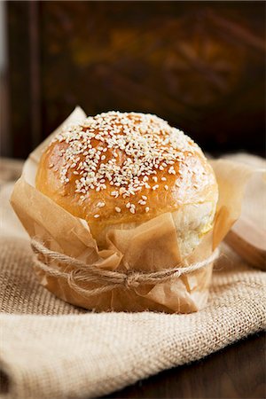 Sesame seed roll wrapped in baking parchment Stock Photo - Premium Royalty-Free, Code: 659-06671254