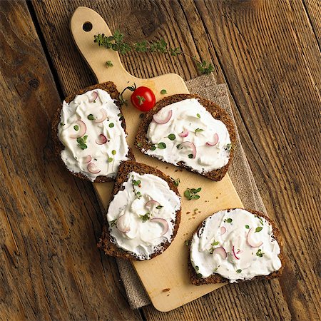 food - Slices of whole grain bread with quark and onions on a wooden board (top view) Stock Photo - Premium Royalty-Free, Code: 659-06902343