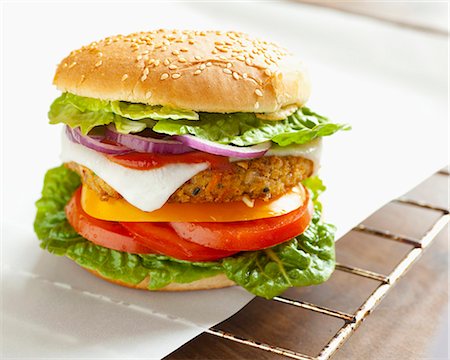 A vegetarian burger with a vegetable patty and goat's cheese, on grease-proof paper on a grill rack Stock Photo - Premium Royalty-Free, Code: 659-06903582