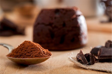 simsearch:659-06151276,k - Chocolate melting middle pudding; cocoa powder and chocolate pieces in front Stock Photo - Premium Royalty-Free, Code: 659-06903987