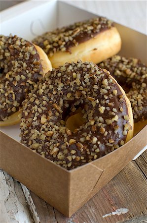 Doughnuts with chocolate glaze and chopped nuts in a box Stock Photo - Premium Royalty-Free, Code: 659-07027361