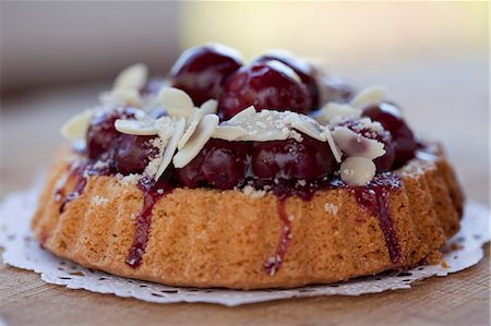 simsearch:659-06188604,k - Individual cherry-topped cake with sliced almonds Stock Photo - Premium Royalty-Free, Code: 659-07027540