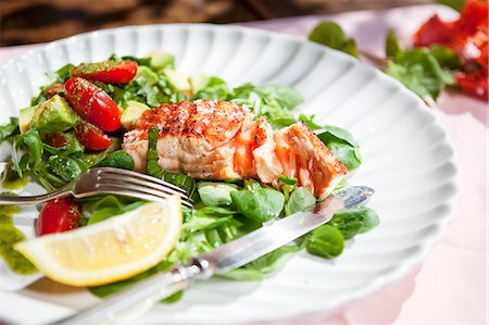 salmon - A salmon fillet on a bed of lamb's lettuce with tomatoes, avocado and pesto Stock Photo - Premium Royalty-Free, Code: 659-07028054