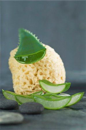 A sliced aloe vera leaf with a sponge luffa and pebbles Stock Photo - Premium Royalty-Free, Code: 659-07028214