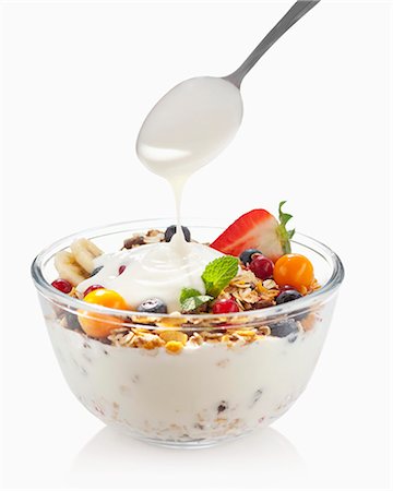 Yoghurt being spooned over a bowl of fruit muesli Stock Photo - Premium Royalty-Free, Code: 659-07028241