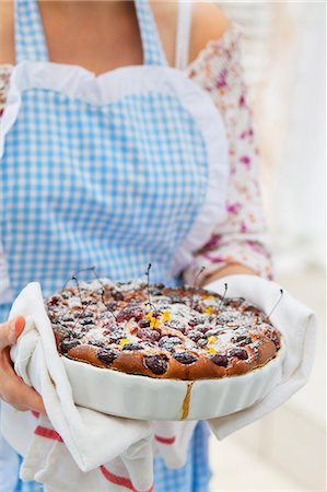 A woman serving cherry cake dusted with icing sugar Stock Photo - Premium Royalty-Free, Code: 659-07068783
