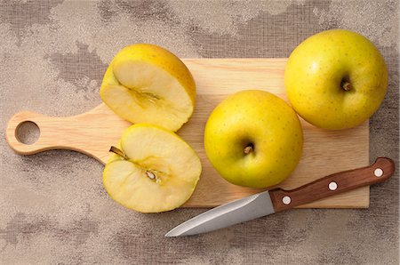 simsearch:659-07069466,k - Golden Delicious apples, whole and halved, on a chopping board Photographie de stock - Premium Libres de Droits, Code: 659-07068967
