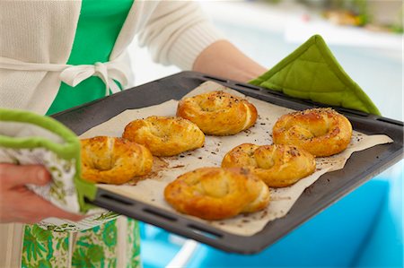 Woman holding baking tray with freshly baked yeast pretzels Stock Photo - Premium Royalty-Free, Code: 659-07597238