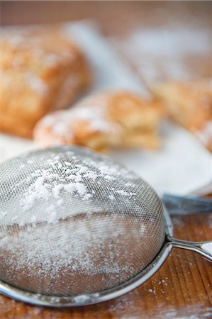 simsearch:659-06188604,k - A sieve with icing sugar, baked pastries in the background Stock Photo - Premium Royalty-Free, Code: 659-07597301