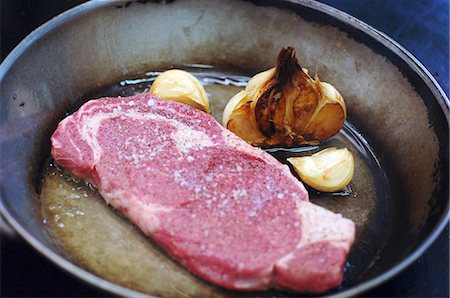 Angus beef steak with garlic in a frying pan Stock Photo - Premium Royalty-Free, Code: 659-07597422