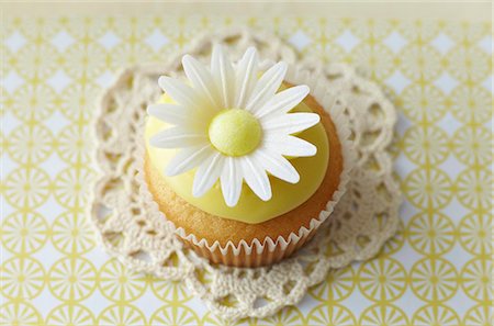 simsearch:659-06903190,k - A cupcake decorated with an oxeye daisy on a lace doily Stock Photo - Premium Royalty-Free, Code: 659-07597524