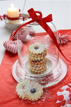 Jam-filled ring biscuits under a glass dome, a fabric heart and a candle Foto de stock - Sin royalties Premium, Código: 659-07597587