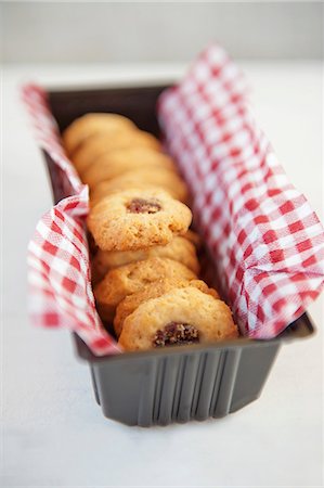 Jam biscuits on a checked napkin in a loaf tin Stock Photo - Premium Royalty-Free, Code: 659-07598804
