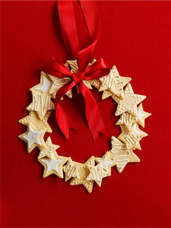 Wreath made of star cookies with a red ribbon in front of a red background Stock Photo - Premium Royalty-Free, Code: 659-07599176