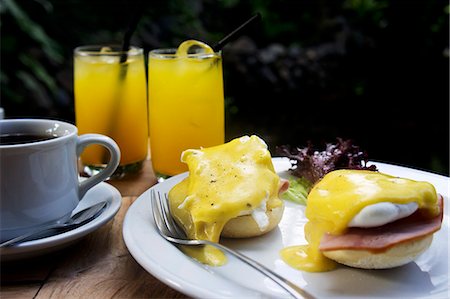 Eggs Benedict with ham served with coffee and juice on a table outside Stock Photo - Premium Royalty-Free, Code: 659-07610162